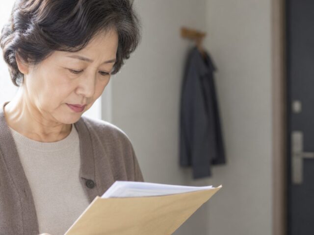 손에 든 봉투를 내려다보는 60대 어르신