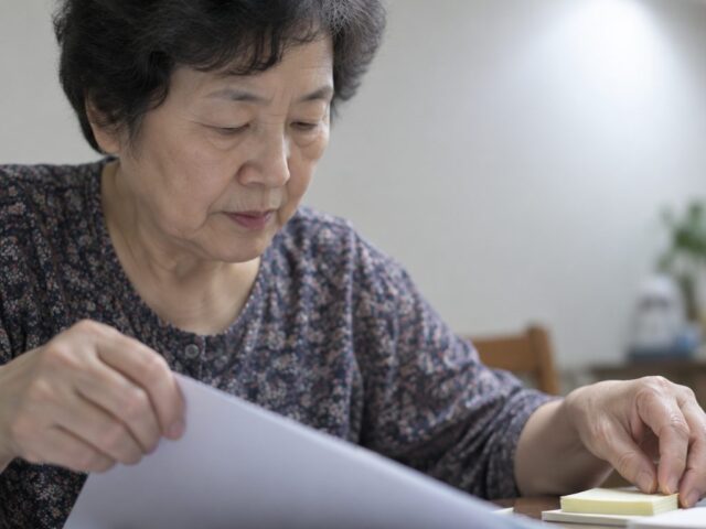 식탁 옆에서 서류를 잡고 메모를 정리하는 어르신