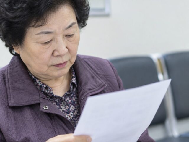 서류를 가슴 높이로 들고 읽는 어르신
