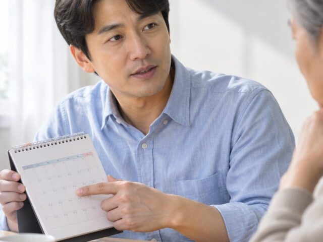 달력을 아버지 쪽으로 내보이는 40대 아들